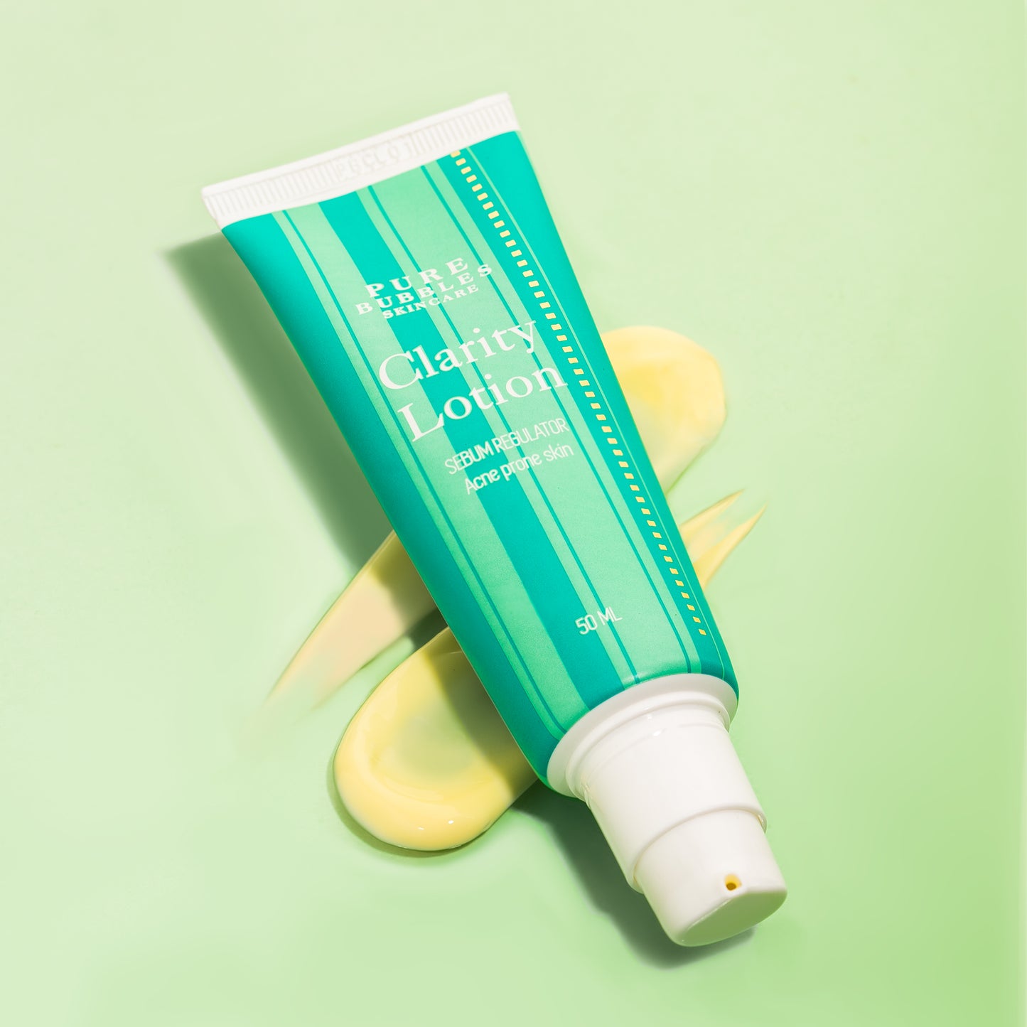 Clarity Lotion for acne prone skin, sebum regulator in green tube with yellow cream swatch on light green background